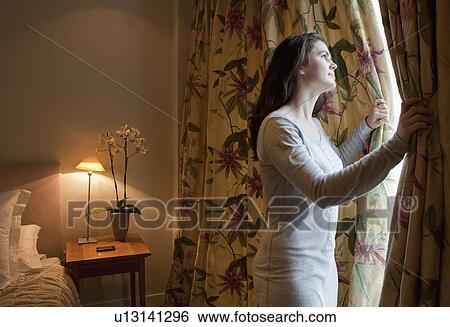 Stock Photograph - Woman opening curtains. Fotosearch