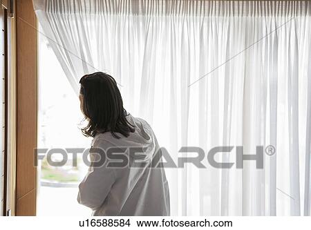 Woman peeping through gap in curtains View Large Photo Image Picture - Woman peeping through gap in curtains. Fotosearch