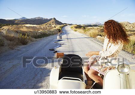 Stock Image - Woman picking up clothes from the road. Fotosearch