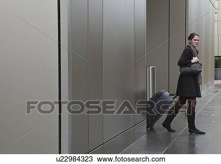 Stock Image - Woman pulling bag on wheels. Fotosearch