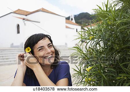Woman putting flower in her hair View Large Photo Image Stock Photo - Woman putting flower in her hair. Fotosearch
