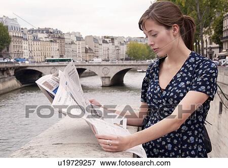 Stock Photo - Woman reads newspaper in Paris. Fotosearch