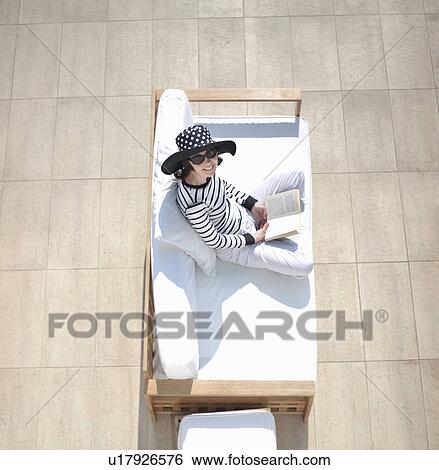 Stock Photograph - Woman relaxing on outdoor sofa. Fotosearch