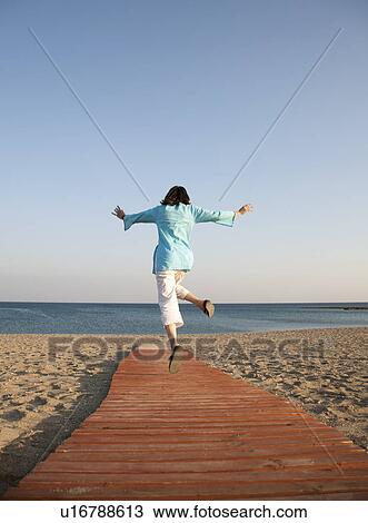 Woman running down boardwalk onto beach View Large Photo Image Stock Image - Woman running down boardwalk onto beach. Fotosearch