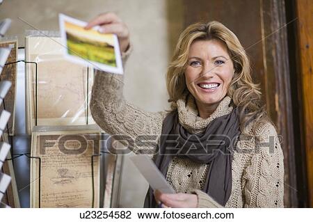 Stock Image - Woman showing a postcard. Fotosearch