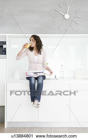 Stock Image - Woman sitting on kitchenette. Fotosearch