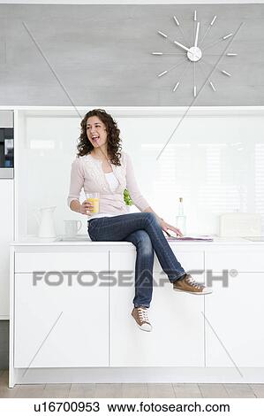 Stock Image - Woman sitting on kitchenette. Fotosearch