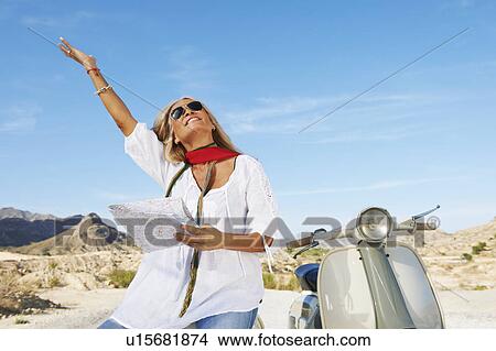 Picture - Woman sitting on motorbike with map. Fotosearch