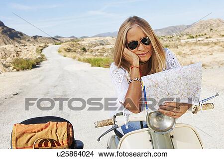 Picture - Woman Sitting on motorbike with map. Fotosearch