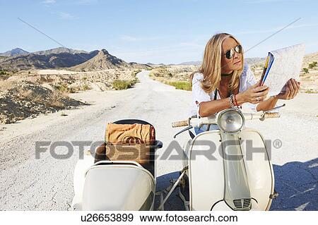 Stock Photo - Woman Sitting on motorbike with map. Fotosearch
