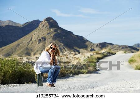 Woman sitting on petrol can in the road View Large Photo Image Picture - Woman sitting on petrol can in the road. Fotosearch