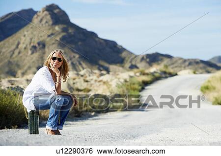 Woman sitting on petrol can in the road View Large Photo Image Stock Photograph - Woman sitting on petrol can in the road. Fotosearch