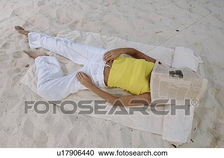 Stock Image - Woman sleeping on beach. Fotosearch