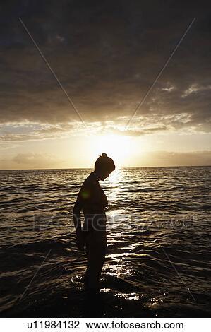 Woman standing in sea by sunset View Large Photo Image Stock Image - Woman standing in sea by sunset. Fotosearch