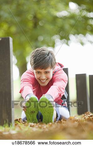 Stock Photograph - Woman stretching in park before workout. Fotosearch