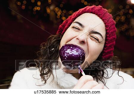 Stock Photography - Woman taking a bite of candied apple. Fotosearch