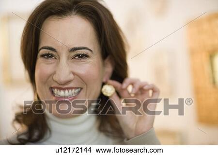 Woman trying on an earring View Large Photo Image Picture - Woman trying on an earring. Fotosearch
