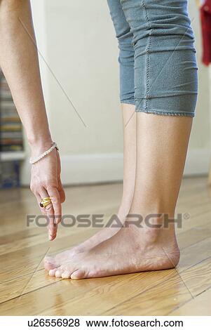 Stock Photo - Woman trying to touch toes at home. Fotosearch