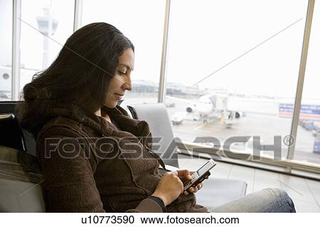 Stock Image - Woman using a smartphone waiting. Fotosearch