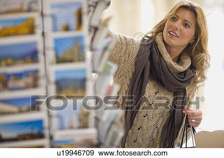 Stock Photo - Woman viewing postcard holder. Fotosearch