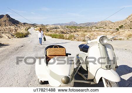 Stock Photo - Woman walking away from motorbike. Fotosearch