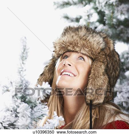 Stock Image - Woman with a faux-fur hat looking above. Fotosearch