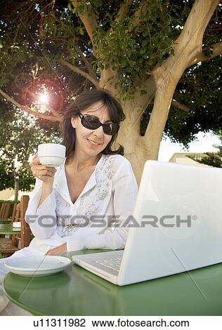 Stock Image - Woman with coffee, working on laptop. Fotosearch
