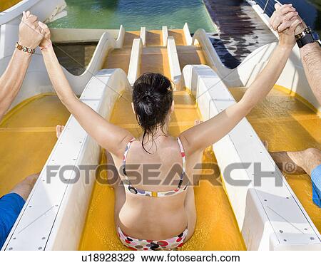 Stock Photo - Woman with friends down swim slide. Fotosearch