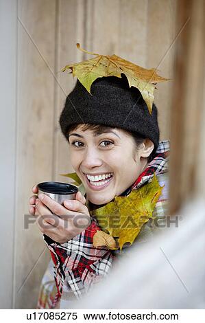 Stock Photography - Woman with leaves and hot drink in hut. Fotosearch