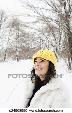 Stock Image - Woman with yellow cap standing in woods. Fotosearch