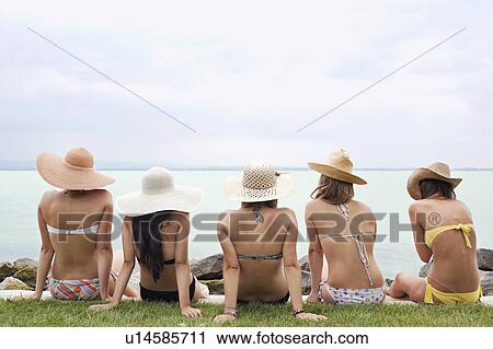 Stock Image - Women in bikinis look out over lake. Fotosearch