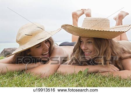 Stock Photograph - Women in straw hats laughing together. Fotosearch