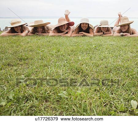 Women in straw hats lie on grass lawn View Large Photo Image Stock Photo - Women in straw hats lie on grass lawn. Fotosearch