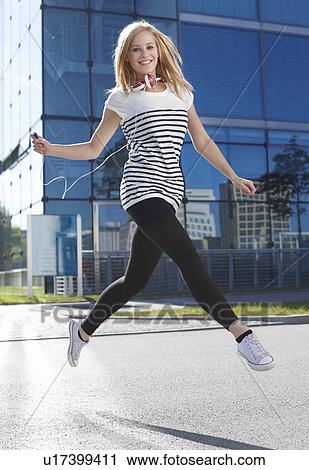 Stock Image - Women jumping with ipod. Fotosearch