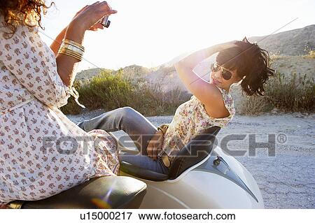 Stock Photo - Women on motorbike taking photos. Fotosearch
