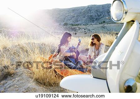 Picture - Women playing the guitar in the grass. Fotosearch