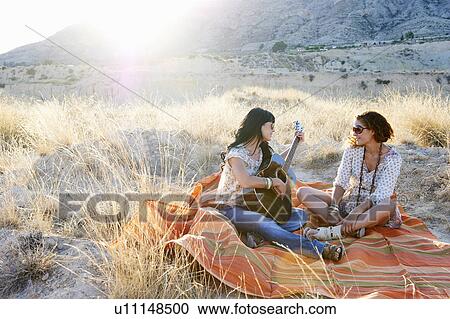 Stock Image - Women playing the guitar in the grass. Fotosearch