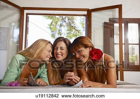 Women relaxing reading magazine together View Large Photo Image Stock Image - Women relaxing reading magazine together. Fotosearch
