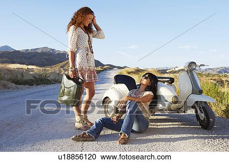 Stock Image - Women resting by road with motorbike. Fotosearch