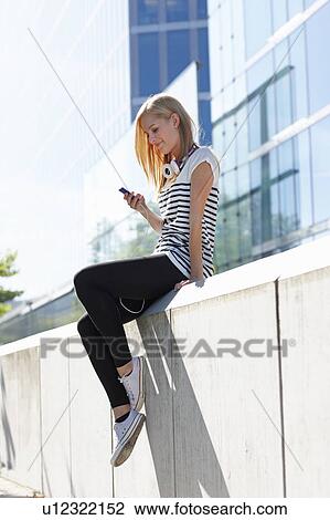 Women sitting on wall with ipod View Large Photo Image Stock Image - Women sitting on wall with ipod. Fotosearch