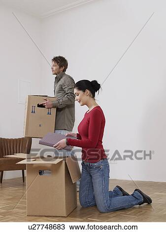 Stock Image - Women unpacks while man helps. Fotosearch