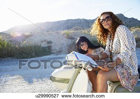 Stock Photo - Women with motorbike looking at map. Fotosearch