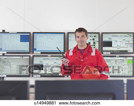 Stock Image - Worker in control room of gas plant. Fotosearch
