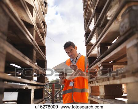 Stock Photo - Worker makes notes next to pallets. Fotosearch