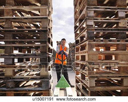 Stock Image - Worker with pallets and pallet truck. Fotosearch