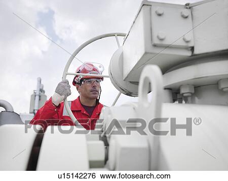 Worker with valve at gas storage plant View Large Photo Image Stock Photograph - Worker with valve at gas storage plant. Fotosearch