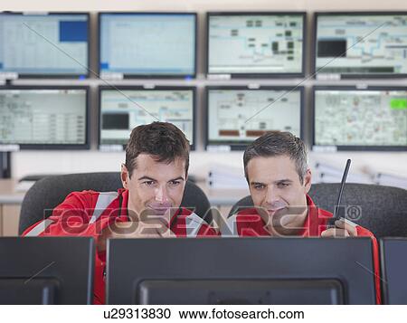 Stock Image - Workers in control room of gas plant. Fotosearch