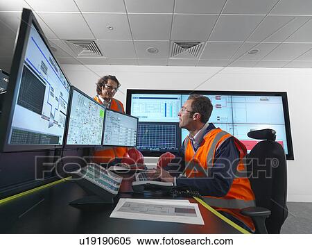 Stock Photography - Workers in control room with screens. Fotosearch