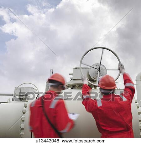 Stock Photo - Workers with valve at gas storage plant. Fotosearch