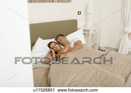 Young attractive couple asleep in bed View Large Photo Image Stock Image - Young attractive couple asleep in bed. Fotosearch